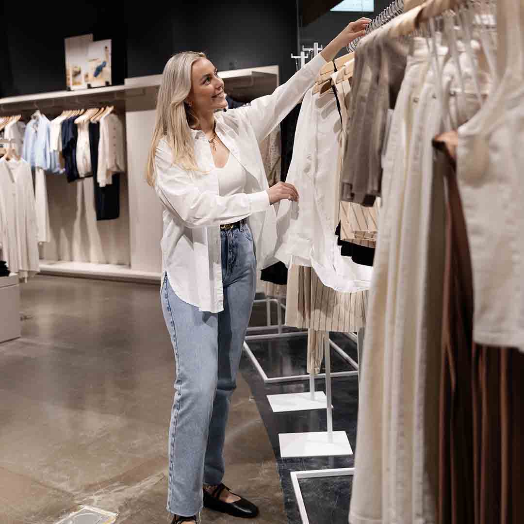 Employee from Selected in Frederiksberg hangs clothes on a rack.